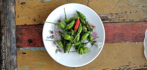 Bird's eye chilies on a white plate. On an aestethic wooden table background. Flat lay photos