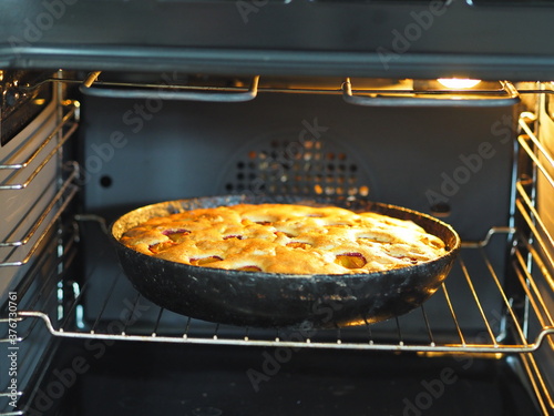 Charlotte with apples and plums is baked in the kitchen oven. Preparation for the holiday.