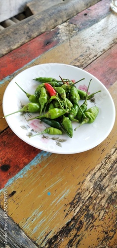 Bird's eye chilies on a white plate. On an aestethic wooden table background. Flat lay photos