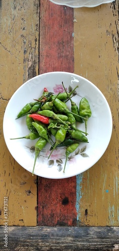 Bird's eye chilies on a white plate. On an aestethic wooden table background. Flat lay photos