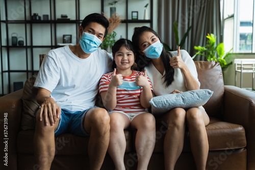 Asian family spending time together at home while wearing face mask. precaution to prevent coronavirus by wearing protective mask.