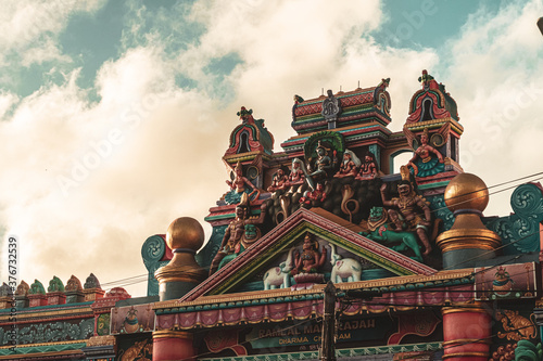 Hindu temple full of colorful ornaments against a blue sky on a sunny day. 