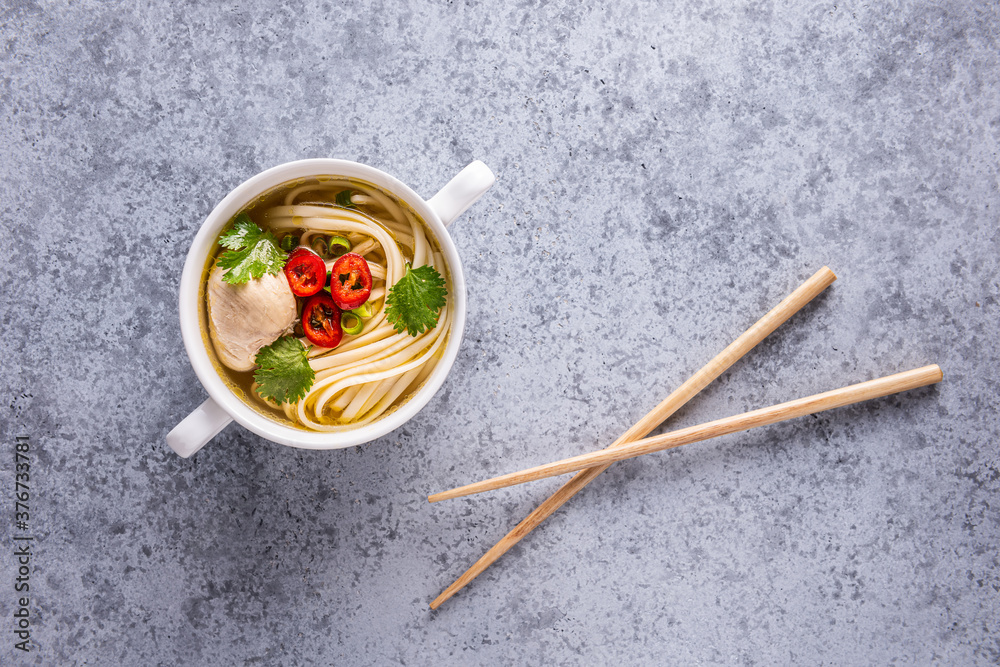 Chicken asian soup and wooden chopsticks on gray Chicken asian soup and wooden chopsticks on gray