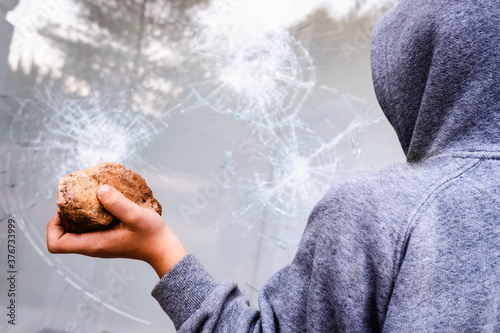 Εκτύπωση καμβά Protester holding a rock to break the glass of a shop window in the street during protests