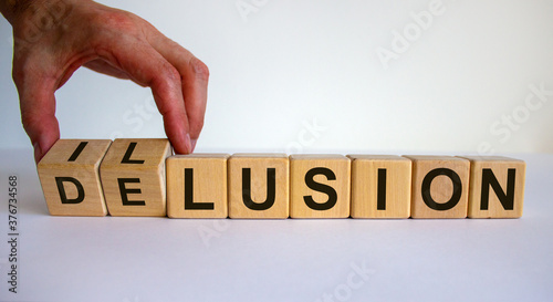Hand turns a cube and changes the word delusion to illusion. Beautiful white background. Business concept. Copy space. photo