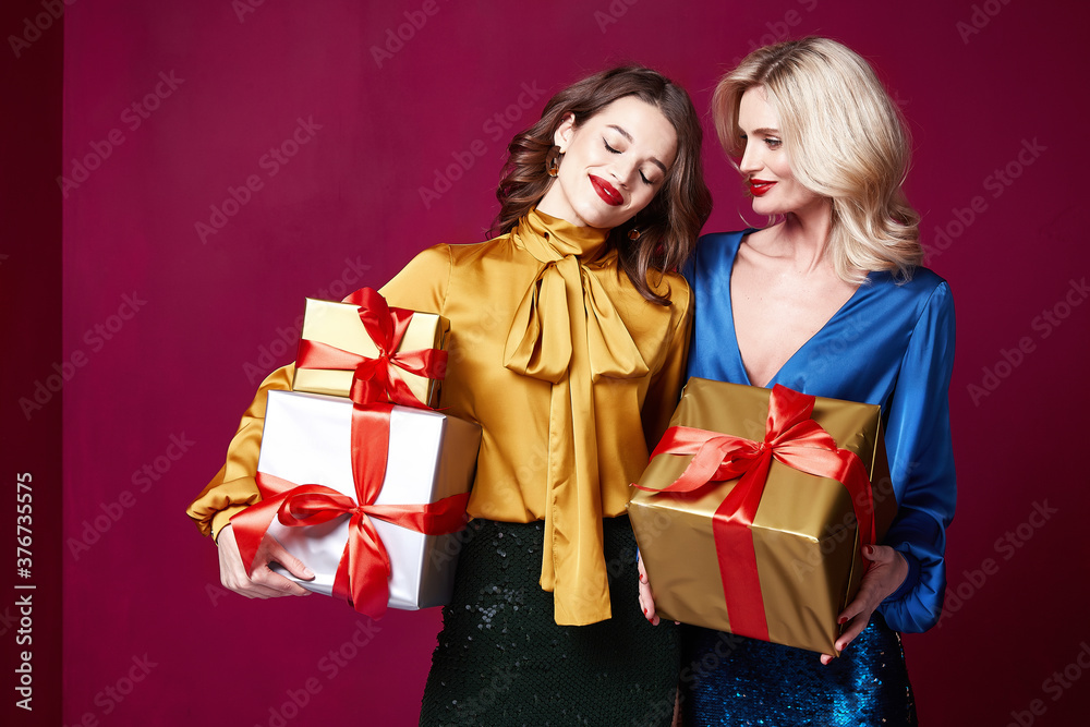 Two beautiful sexy young woman bright evening make-up red lips long fluffy eyelashes hold gift box holiday New Year joy fun happy merry Christmas Eve party celebration St. Valentine's Day girlfriend. Two beautiful sexy young woman bright evening make-up red lips long fluffy eyelashes hold gift box holiday New Year joy fun happy merry Christmas Eve party celebration St. Valentine's Day girlfriend.