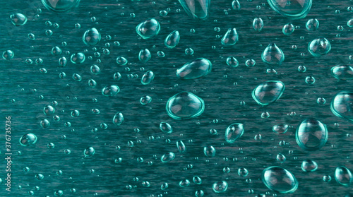 Abstract green aluminum foil with water drops, close-up, macro background texture. Metal foil background pattern