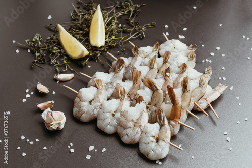 Fresh shrimps with lemon and thyme on skewers.