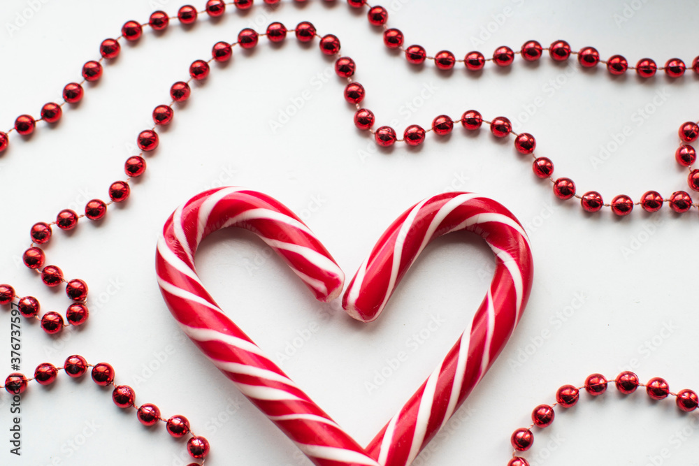 Christmas candy in the shape of a heart among Christmas garlands on a white background. the view from the top. decoration for Christmas Christmas candy in the shape of a heart among Christmas garlands on a white background. the view from the top. decoration for Christmas
