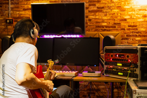 back of male musician enjoy playing electric guitar in home recording studio