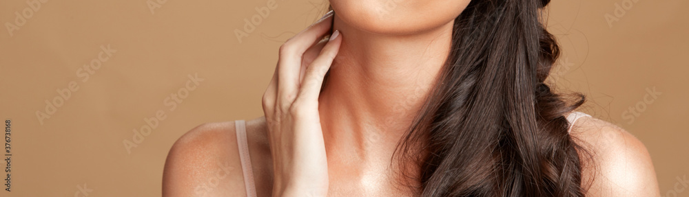 Women with long brown hair, neck and shoulders with hand touching chin Women with long brown hair, neck and shoulders with hand touching chin