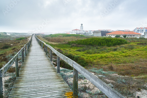 a wooden walkway in the coastal dunes; cloudy skies and fog in the distance