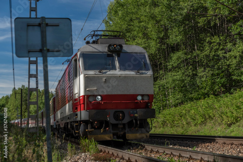 Red fast passenger train on main railway in Slovakia near Vysoke Tatry mountains