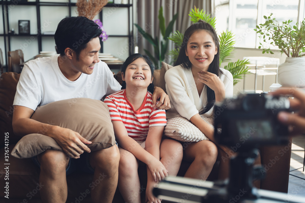 Scene of Asian happy family while take a photograph together by digital camera at home during self isolation from covid 19 pandemic.