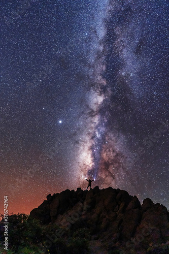 A young woman below the beautiful milky way of the Caldera de Taburiente near the Roque de los Muchahos on the island of La Palma, Canary Islands. Spain, astrophotography