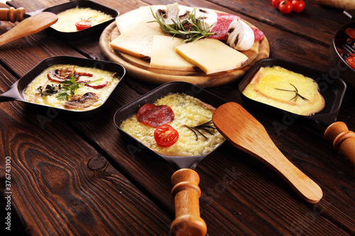 Photography Delicious traditional Swiss melted raclette cheese served in individual skillets