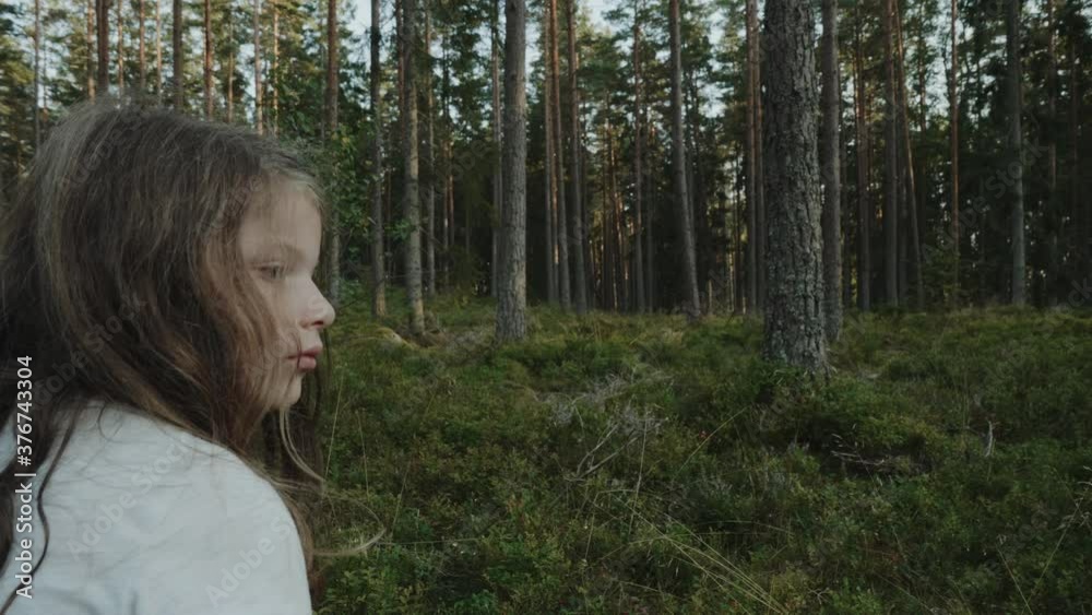 A girl stands still and looks around in a large green forest A girl stands still and looks around in a large green forest