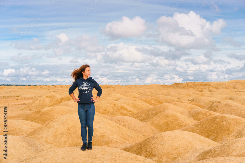 A young woman with long hair walks through the desert with sand dunes of a bizarre shape A young woman with long hair walks through the desert with sand dunes of a bizarre shape