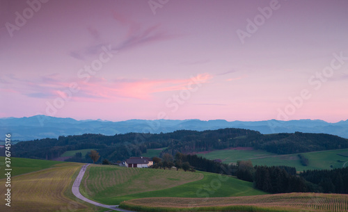 Amazing green hills landscape on pink sunset. alpine farmland Austria, Europe. colorful Violet and pink