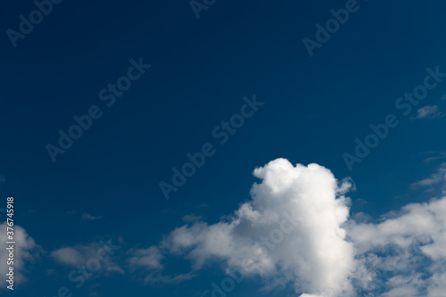 White cotton wool clouds on a sunny day. A continuous stream of clouds across the summer sky.