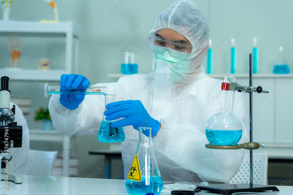 Asian medical scientist in protective white jumpsuit and glasses and face mask diagnosis virus with microscope in clinical laboratory