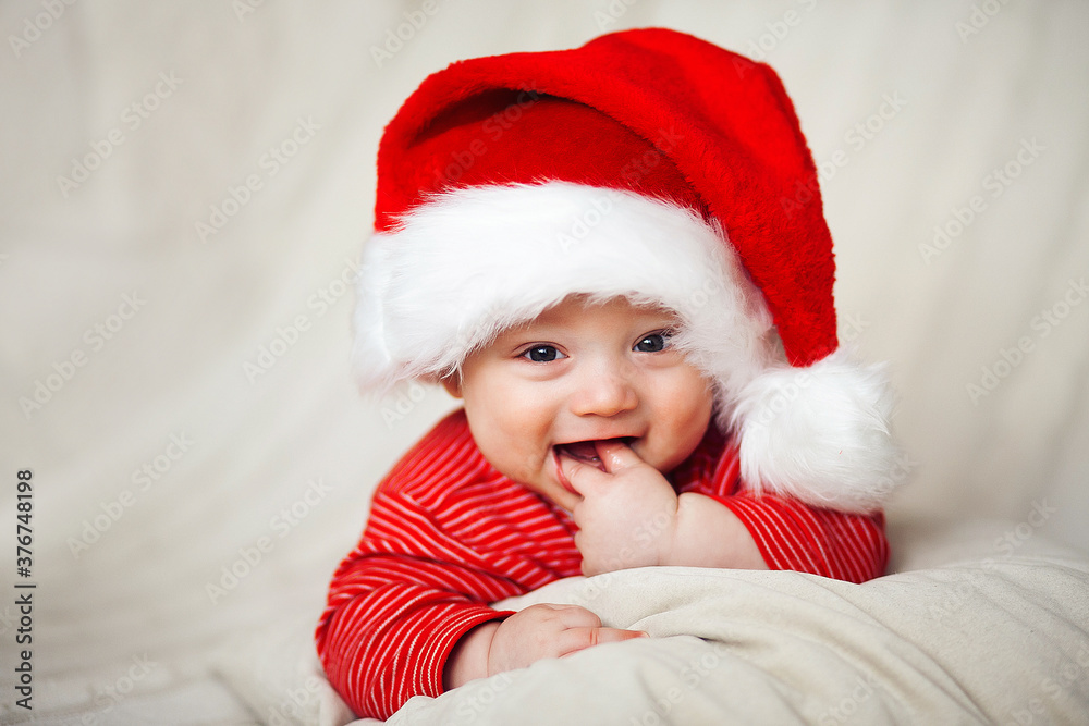 Smiling happy baby in christmas santa's hat and red overalls Smiling happy baby in christmas santa's hat and red overalls