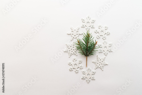 Christmas fresh spruce branch with white snowflakes on a white background. minimalistic concept. Flat lay  top view  where you want to copy.