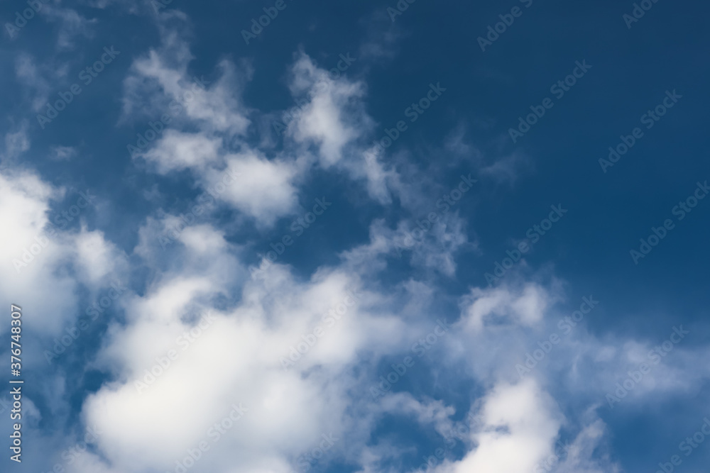 Obraz premium White cotton wool clouds on a sunny day. A continuous stream of clouds across the summer sky.