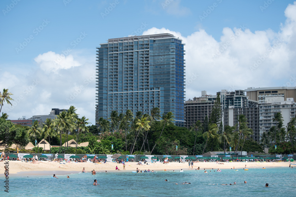 Hotel oceanfront on a sunny white sand beach on Waikiki Honolulu in Hawaii with tourist and beachgoers enjoying water outdoor activities Hotel oceanfront on a sunny white sand beach on Waikiki Honolulu in Hawaii with tourist and beachgoers enjoying water outdoor activities