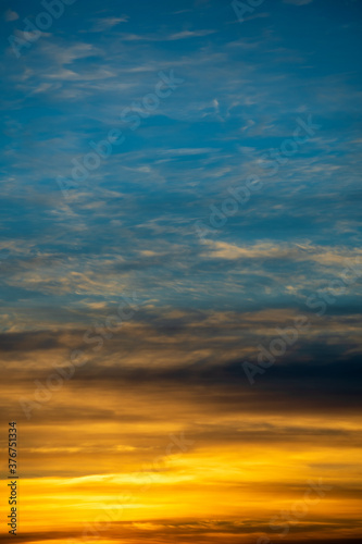 Golden and blue sky with white clouds during sunset © OlegD