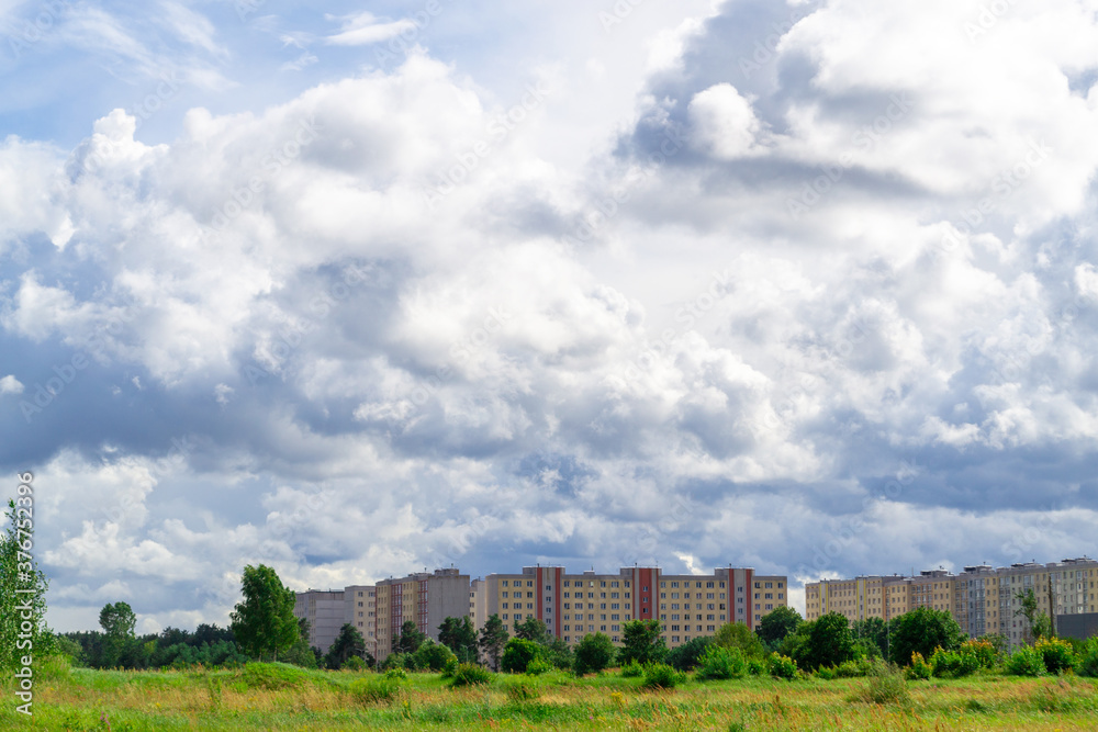 Dreilini microdistrict, Riga, Latvia.  Nine storey buildings built in the 90s. And a green pone in the foreground. Gray cumulus dramatic clouds.
