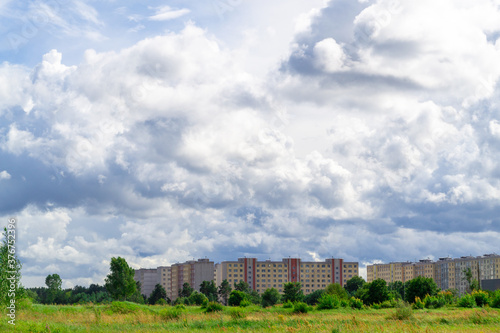 Dreilini microdistrict, Riga, Latvia. Nine storey buildings built in the 90s. And a green pone in the foreground. Gray cumulus dramatic clouds.