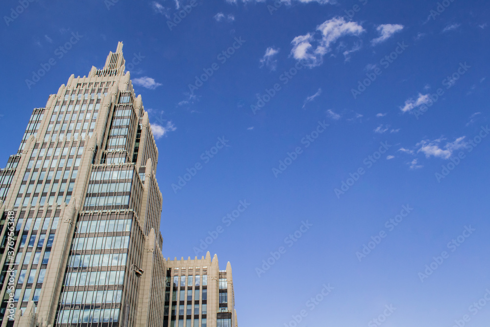 A pointed tower of an office building against a blue sky with clouds. Copy space