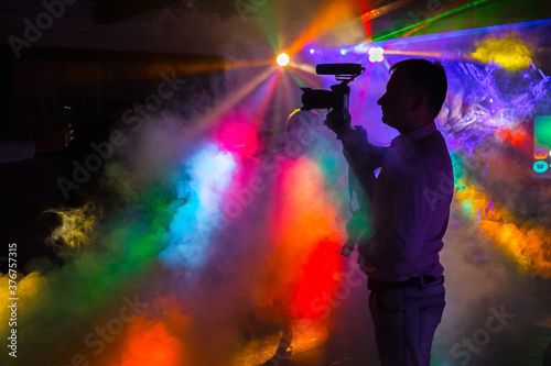 a man with a camera shoots a video at a disco with neon rays