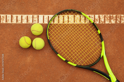 Tennis racquet with tennis balls on clay court © Atlas