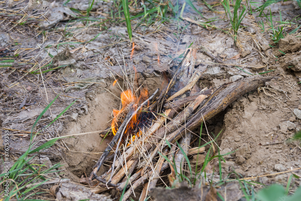 Lighting a fire on a picnic. The firewood is burned in a specially dug pit to avoid fire Lighting a fire on a picnic. The firewood is burned in a specially dug pit to avoid fire