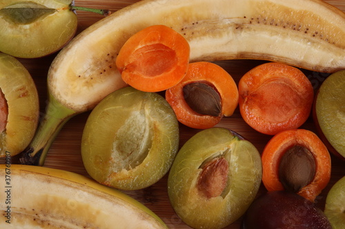Slices of ripe fruits. Ripe juicy apricots, plums and bananas on a wooden board. Ripe fruits composition. Healthy food.