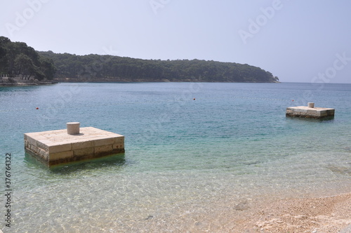 Small stone dock on island beach, Cikat bay, Island Losinj, Croatia.