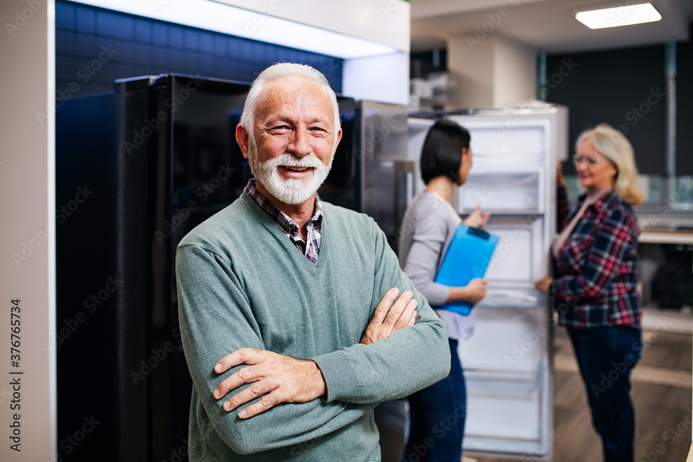 Senior husband and wife talking with saleswoman in appliances store. Senior husband and wife talking with saleswoman in appliances store.