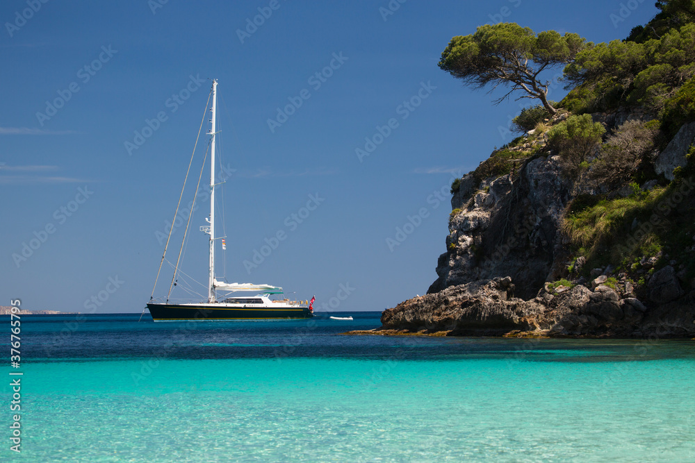 Coastal view with yacht on horizon, Cala Macarelleta, Menorca, Spain Coastal view with yacht on horizon, Cala Macarelleta, Menorca, Spain