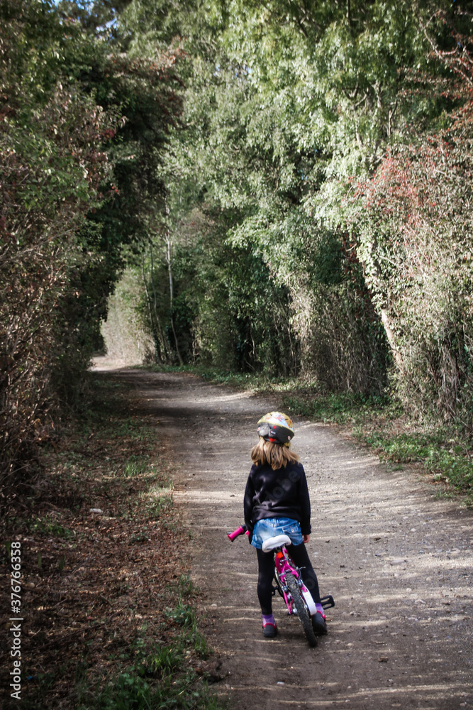 petite fille sur son vélo sur un chemin de campagne