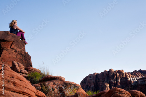 Female hiker looking out from top of rock formation in Snow Canyon State Park, Utah, USA