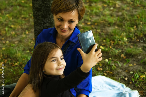 Mother and her little daughter are taking selfie in the park. photo