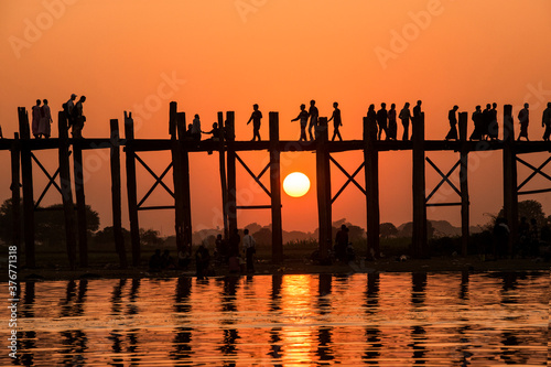 People walking over Bein Bridge at sunset, Amarapura, Mandalay, Myanmar photo