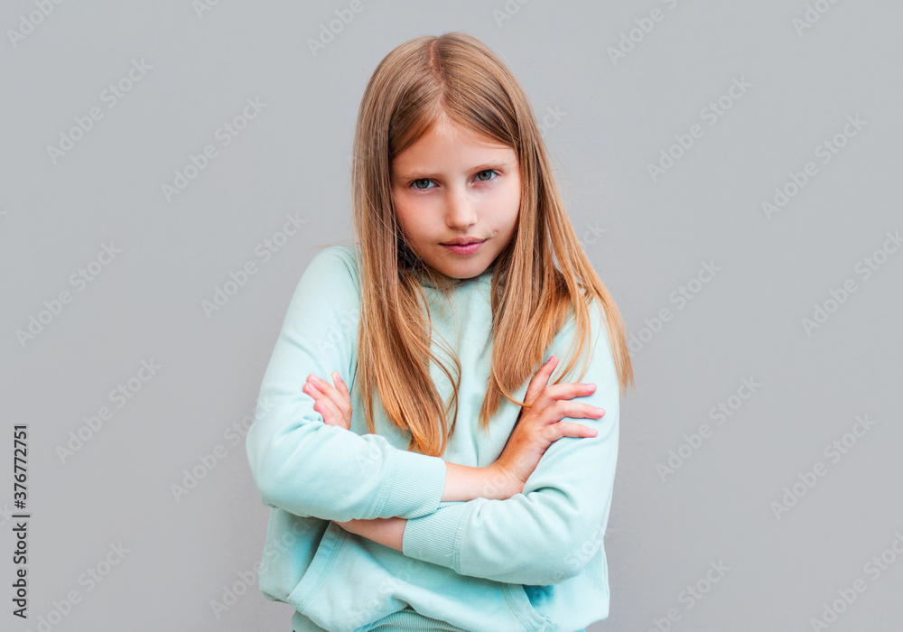 Frustrated upset lonely little girl standing in closed pose isolated on gray studio background, lonely offended blonde kid weeping feel unhappy, anxiety disorder or naughty bad behavior concept Frustrated upset lonely little girl standing in closed pose isolated on gray studio background, lonely offended blonde kid weeping feel unhappy, anxiety disorder or naughty bad behavior concept
