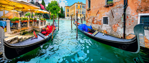 Wharf with gondolas by cafe on Grand Canal. Venice, Italy