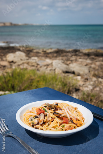 Bowl of seafood pasta on restaurant table at coast, Puglia, Italy