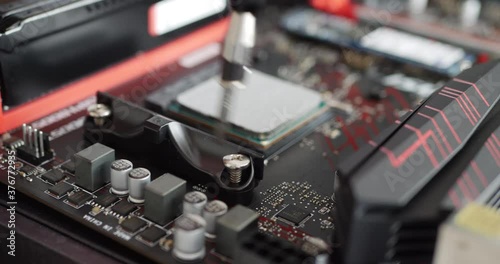 A computer repair technician installing a new gaming pc cpu on a motherboard with a screw driver tool. photo