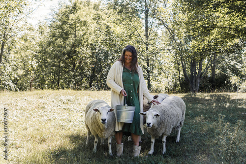 Smiling woman with sheep standing on farm photo