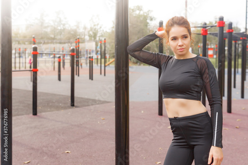 Beautiful attractive asian brunette in black tracksuit doing exercises in the park in the morning